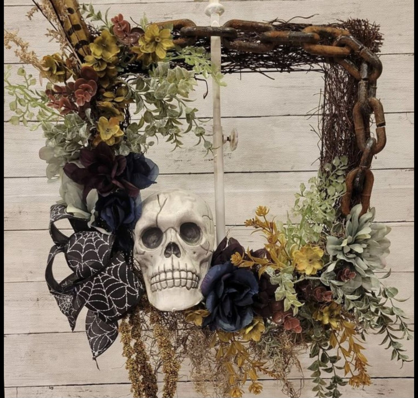 Spooky Wreath Workshop example with skull, flowers, web ribbon, and rustic frame