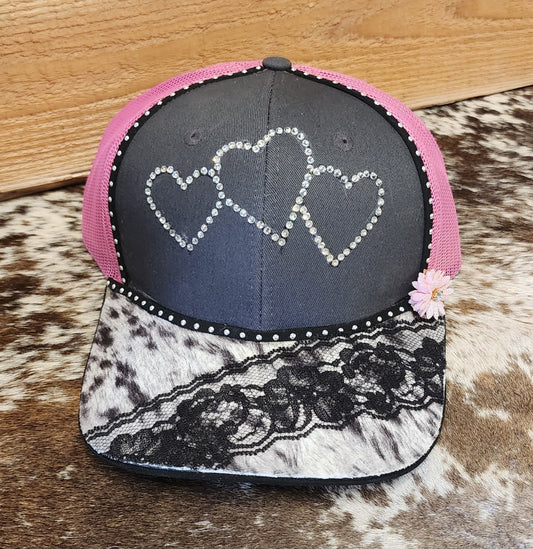 One-of-a-kind handcrafted snapback with three rhinestone hearts, pink mesh, cowhide-patterned bill and black lace
